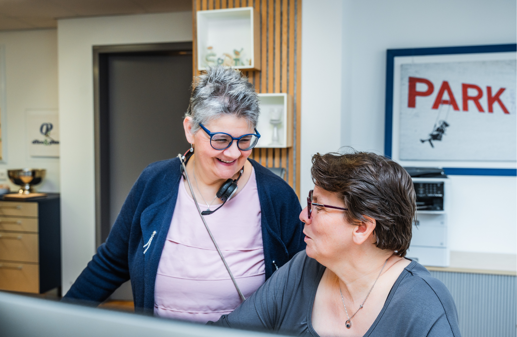 Zwei Beschäftigte von Büromanagement-Unternehmen office & phone unterhalten sich an einem Arbeitsplatz.